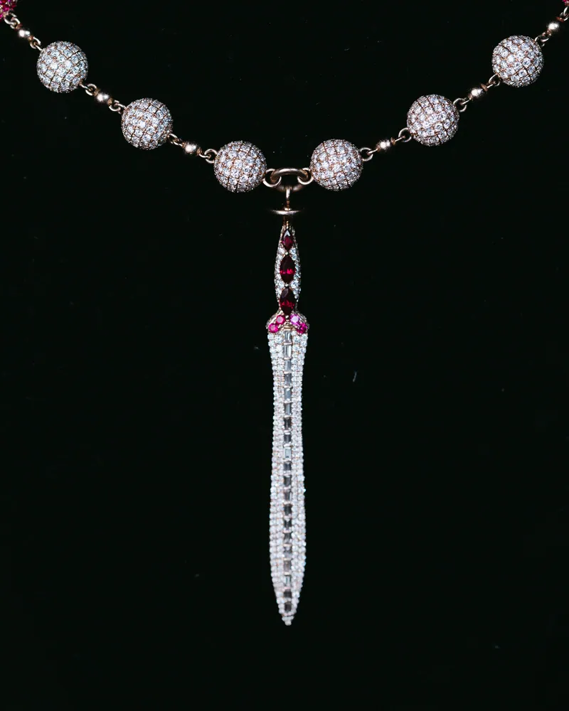 Stone-set blade-shaped pendant hanging from a bead necklace